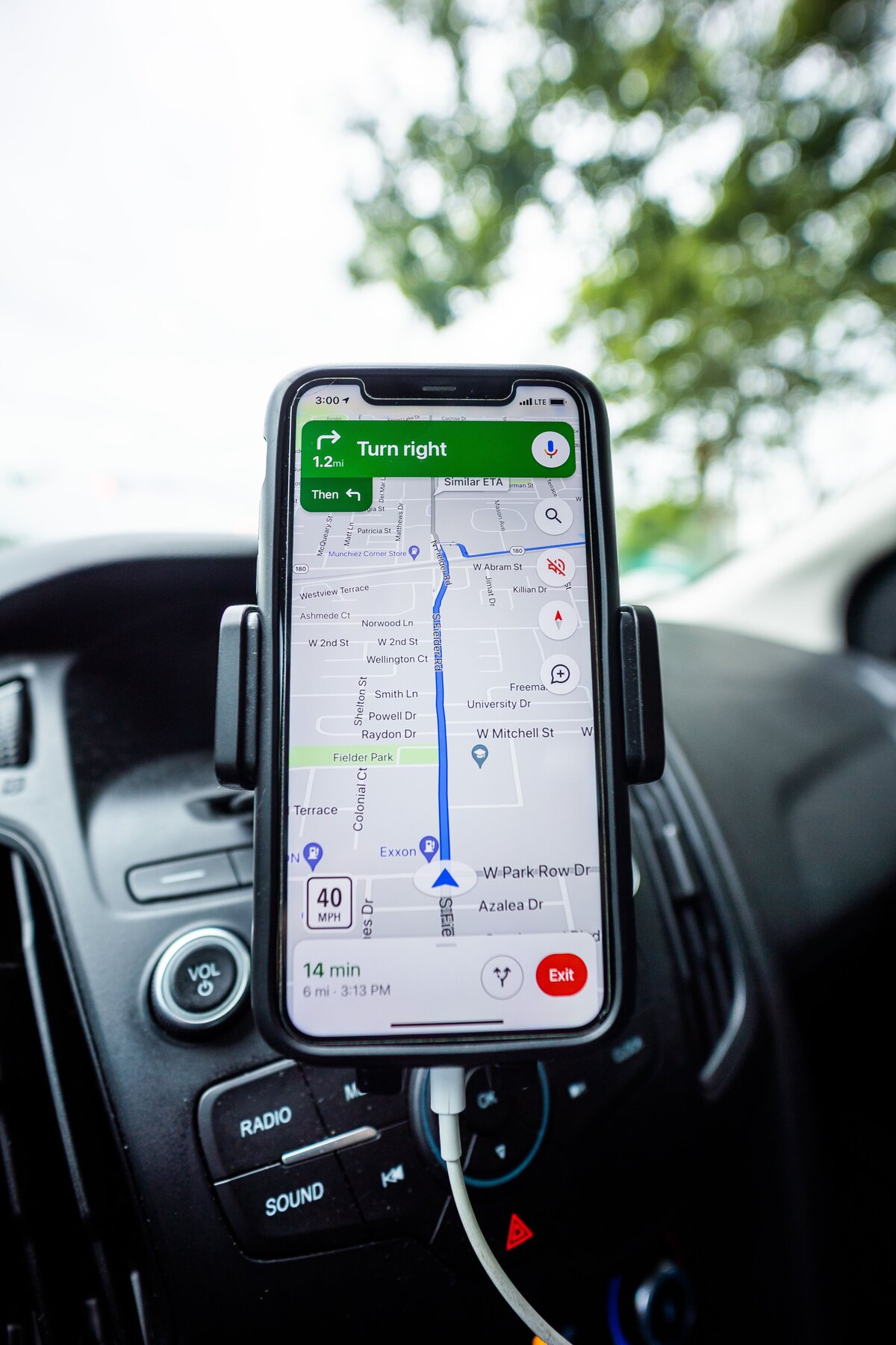 A phone mounted on a car dashboard showing turn-by-turn navigation